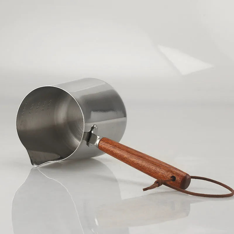 Stainless steel barista milk jug with measurement scale and wooden handle shown in 350ml, 600ml, and 1000ml sizes.