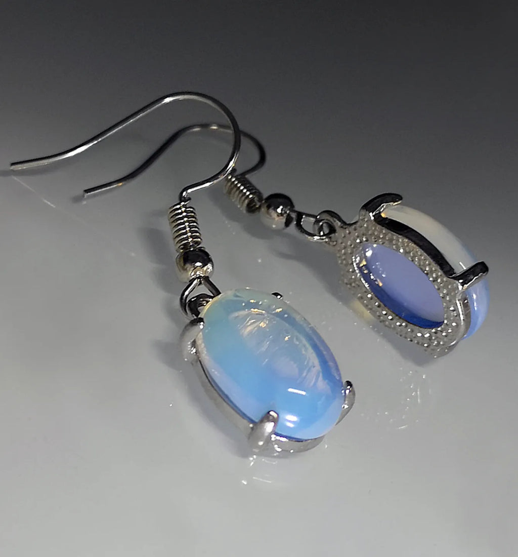 A pair of retro drop-shaped earrings with a cross design in moonlight opal colour on a white background.