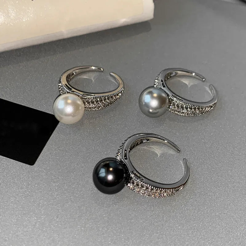 Adjustable black geometric pearl copper ring for women on a finger.
