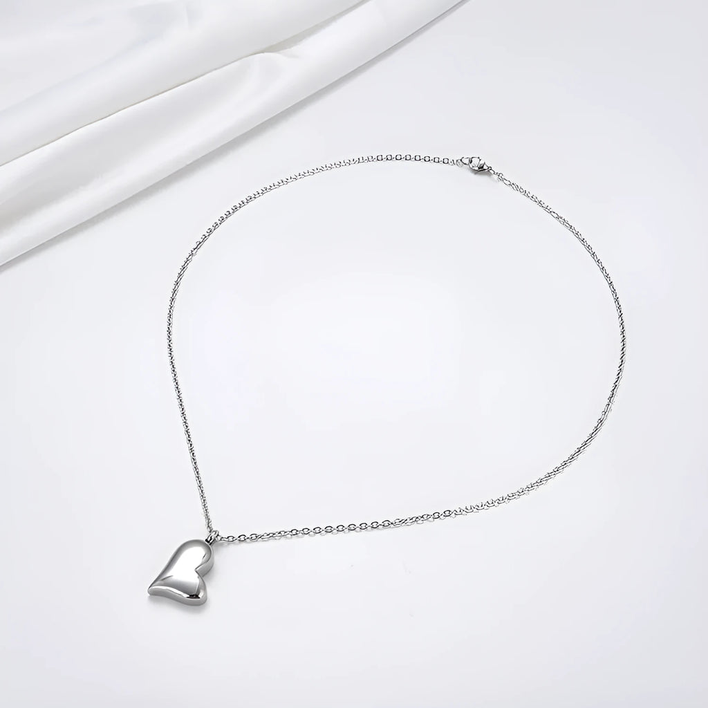 Silver stainless steel necklace with a curved peach heart pendant on an adjustable chain.