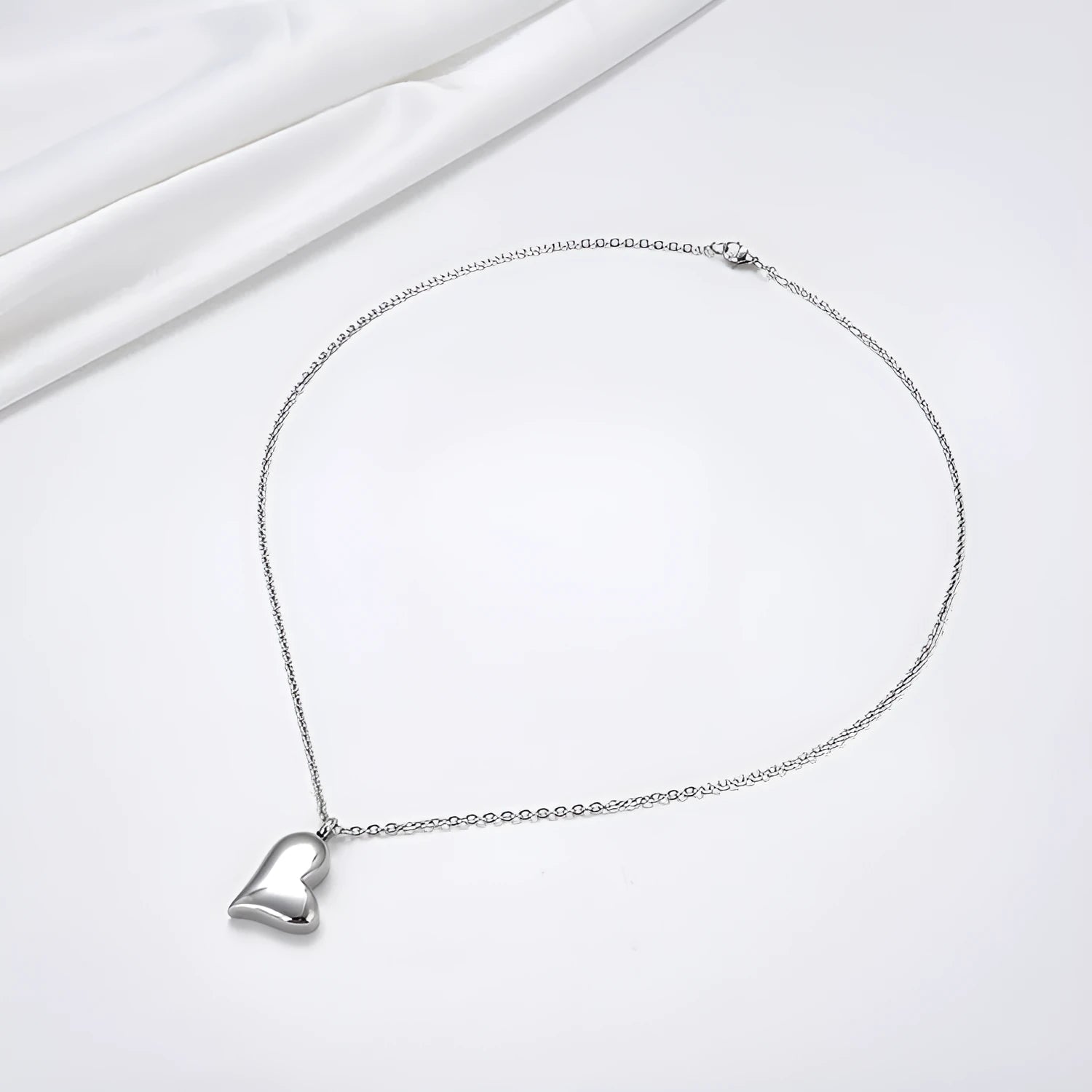Silver stainless steel necklace with a curved peach heart pendant on an adjustable chain.