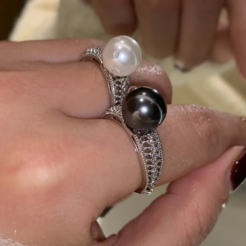 Adjustable black geometric pearl copper ring for women on a finger.