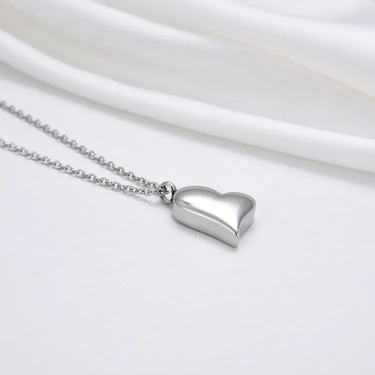 Silver stainless steel necklace with a curved peach heart pendant on an adjustable chain.