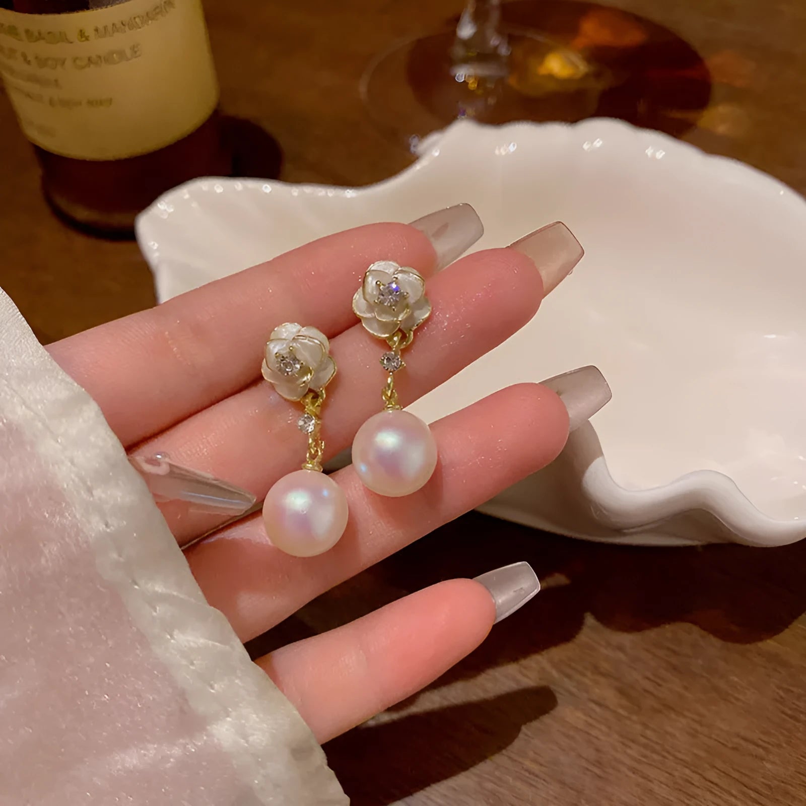 A pair of alloy camellia flower stud earrings for women with a faux pearl centre.