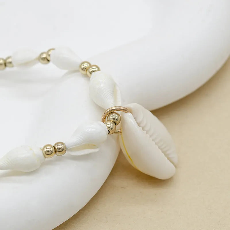 White conch shell necklace with mother of pearl pendant and beads on a chain.