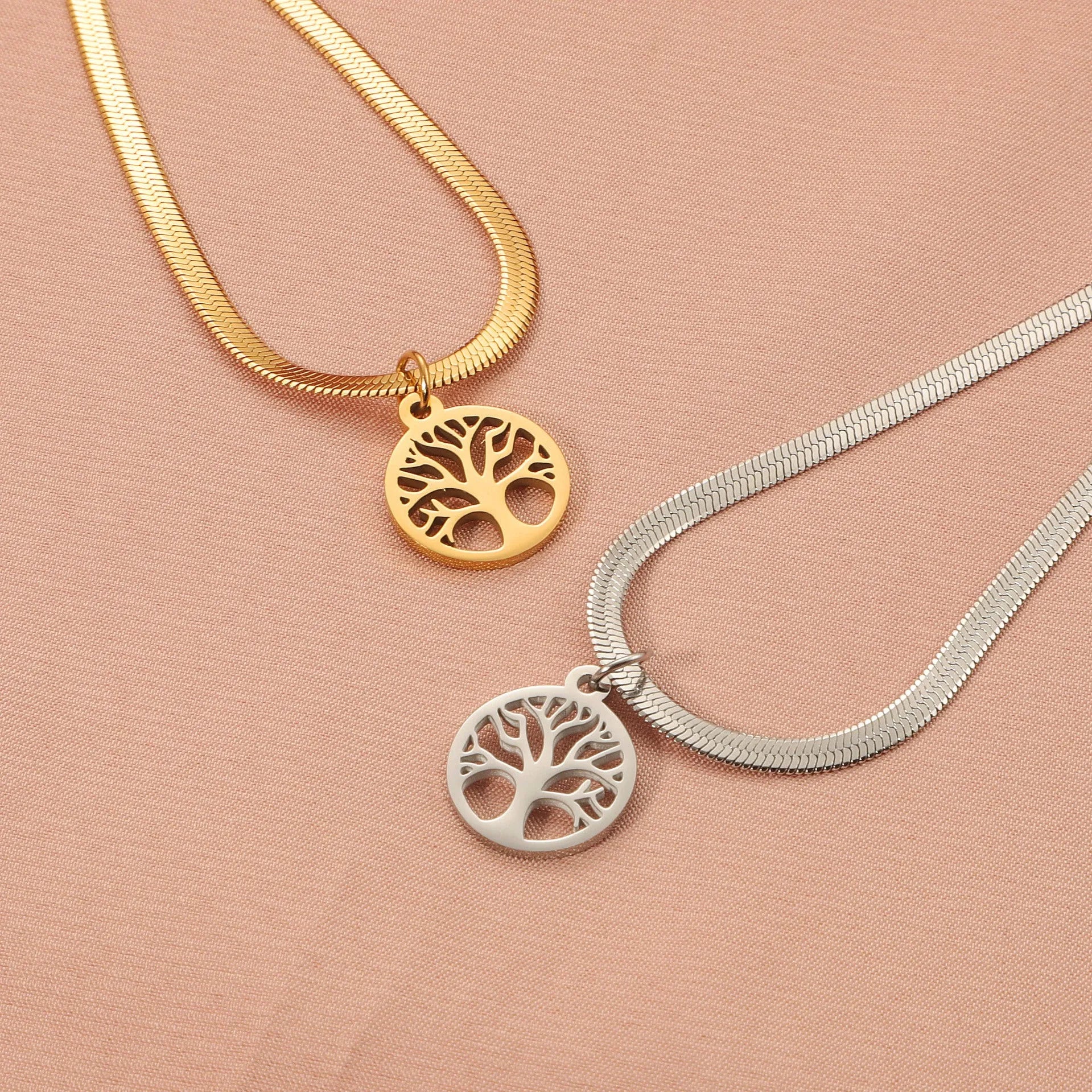 Gold tone lucky tree pendant necklace on a textured snake chain against a plain background.