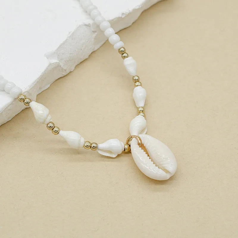 White conch shell necklace with mother of pearl pendant and beads on a chain.
