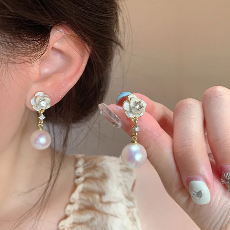 A pair of alloy camellia flower stud earrings for women with a faux pearl centre.