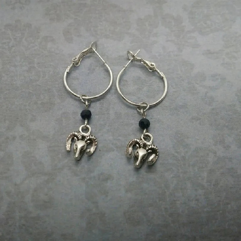 Silver Tibetan antelope round ring drop dangle earrings on a white background.