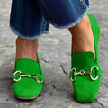 Green suede flat loafers with a round toe and silver metal fastener on the front.