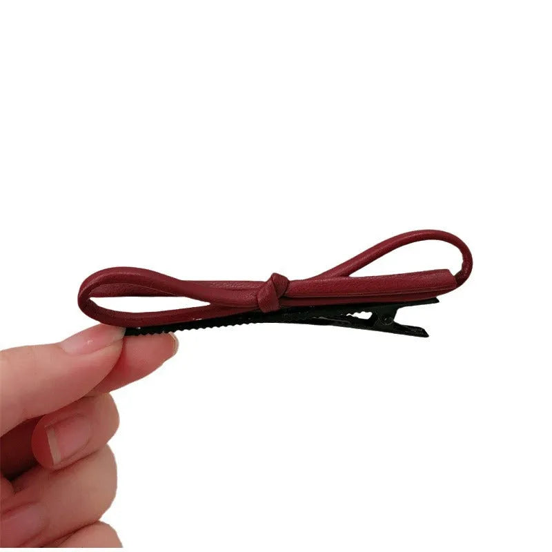 Wine red leather bow hair clip barrette on a white background.