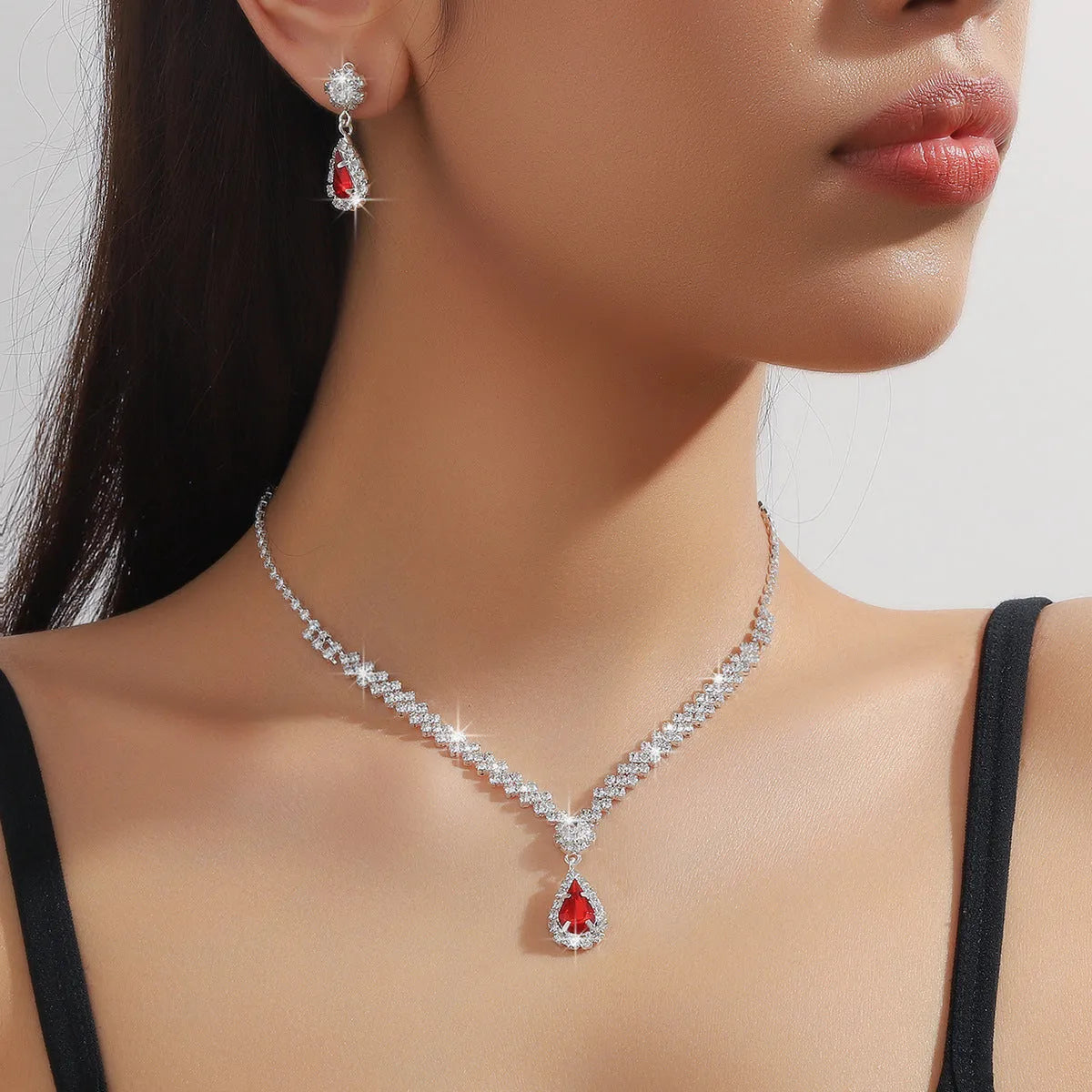 Women's rhinestone water drop necklace and earrings set on a claw chain in blue colour.