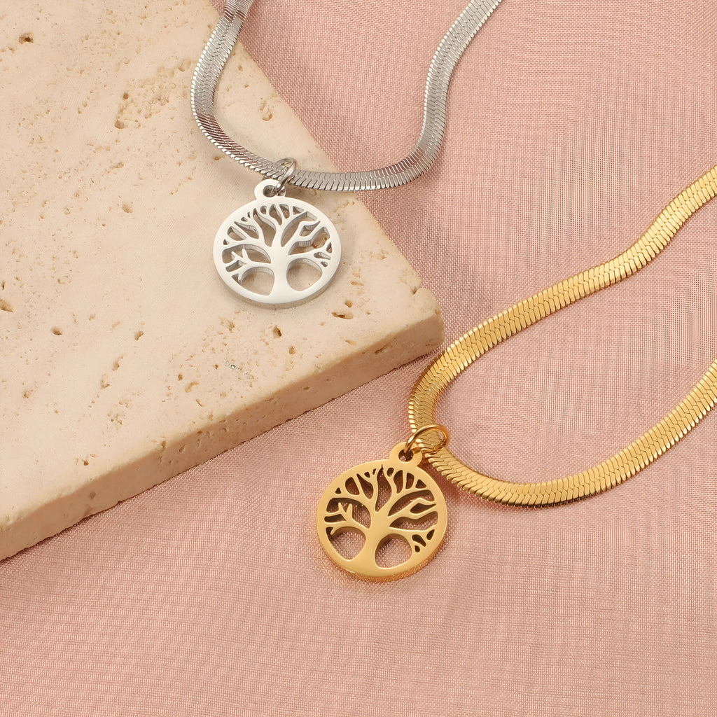 Gold tone lucky tree pendant necklace on a textured snake chain against a plain background.