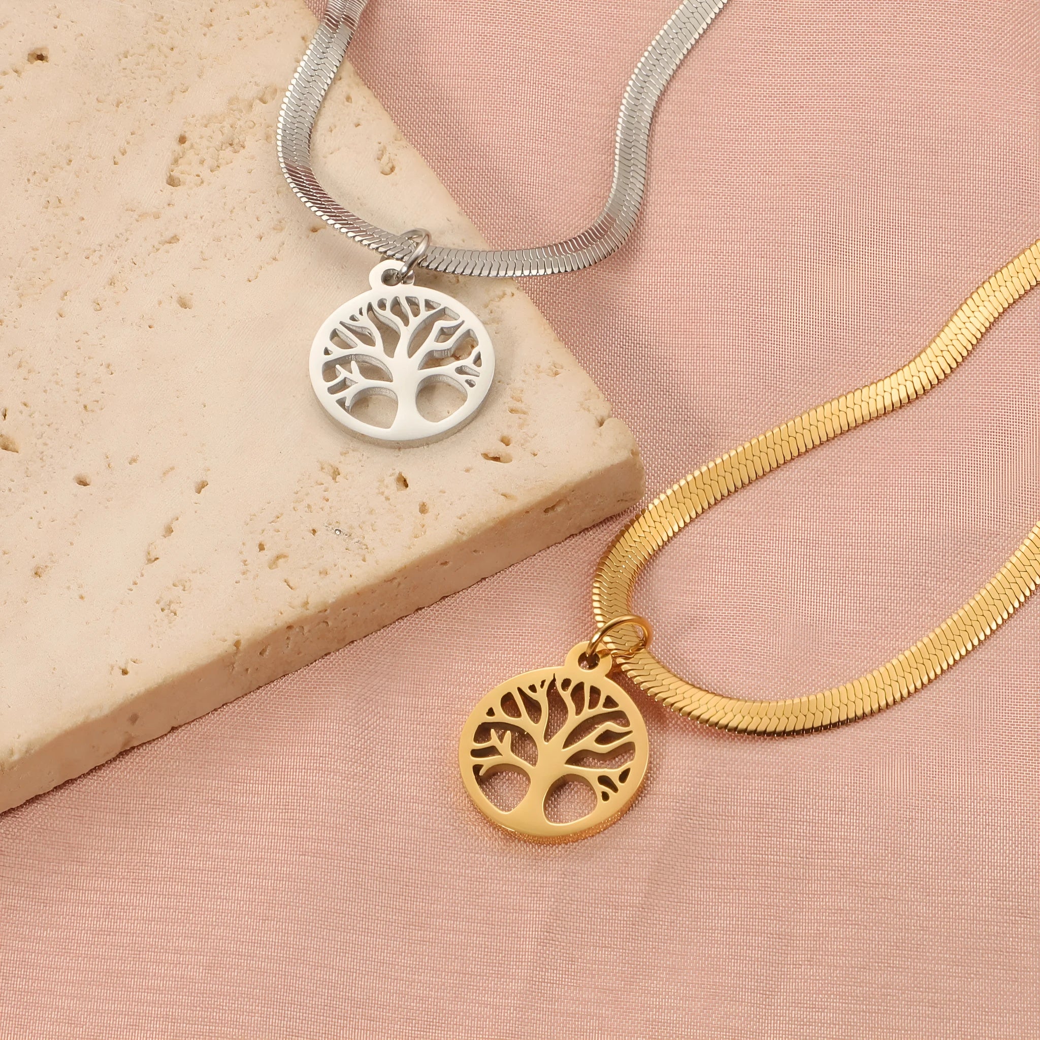 Gold tone lucky tree pendant necklace on a textured snake chain against a plain background.