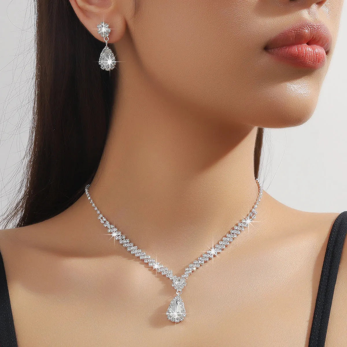 Women's rhinestone water drop necklace and earrings set on a claw chain in blue colour.