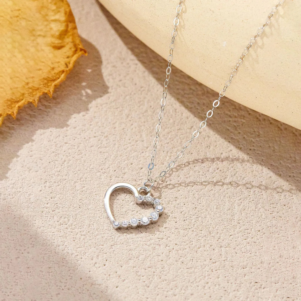 Sterling silver hollow heart pendant necklace on a classic chain, available in white gold or 18K gold plating.