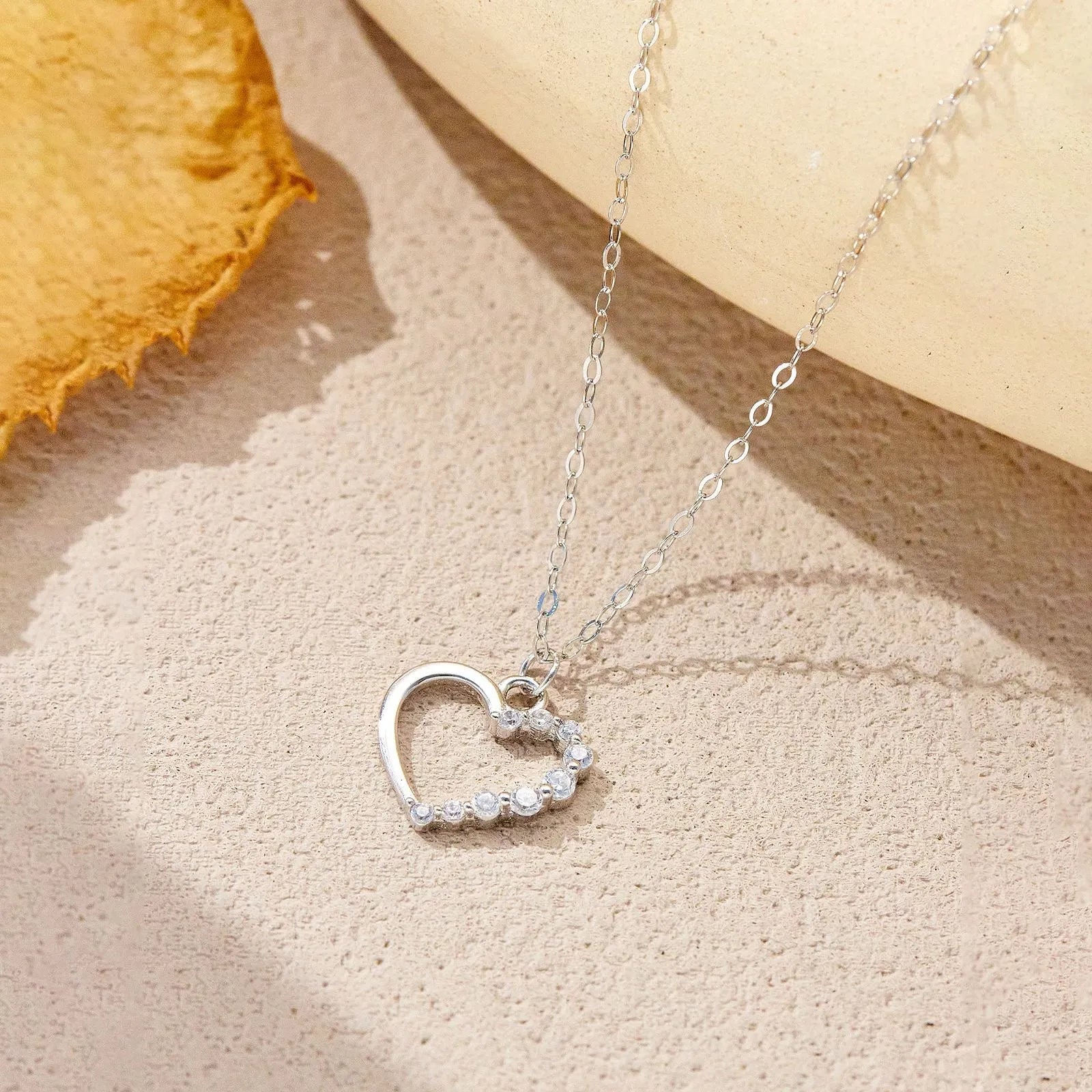 Sterling silver hollow heart pendant necklace on a classic chain, available in white gold or 18K gold plating.