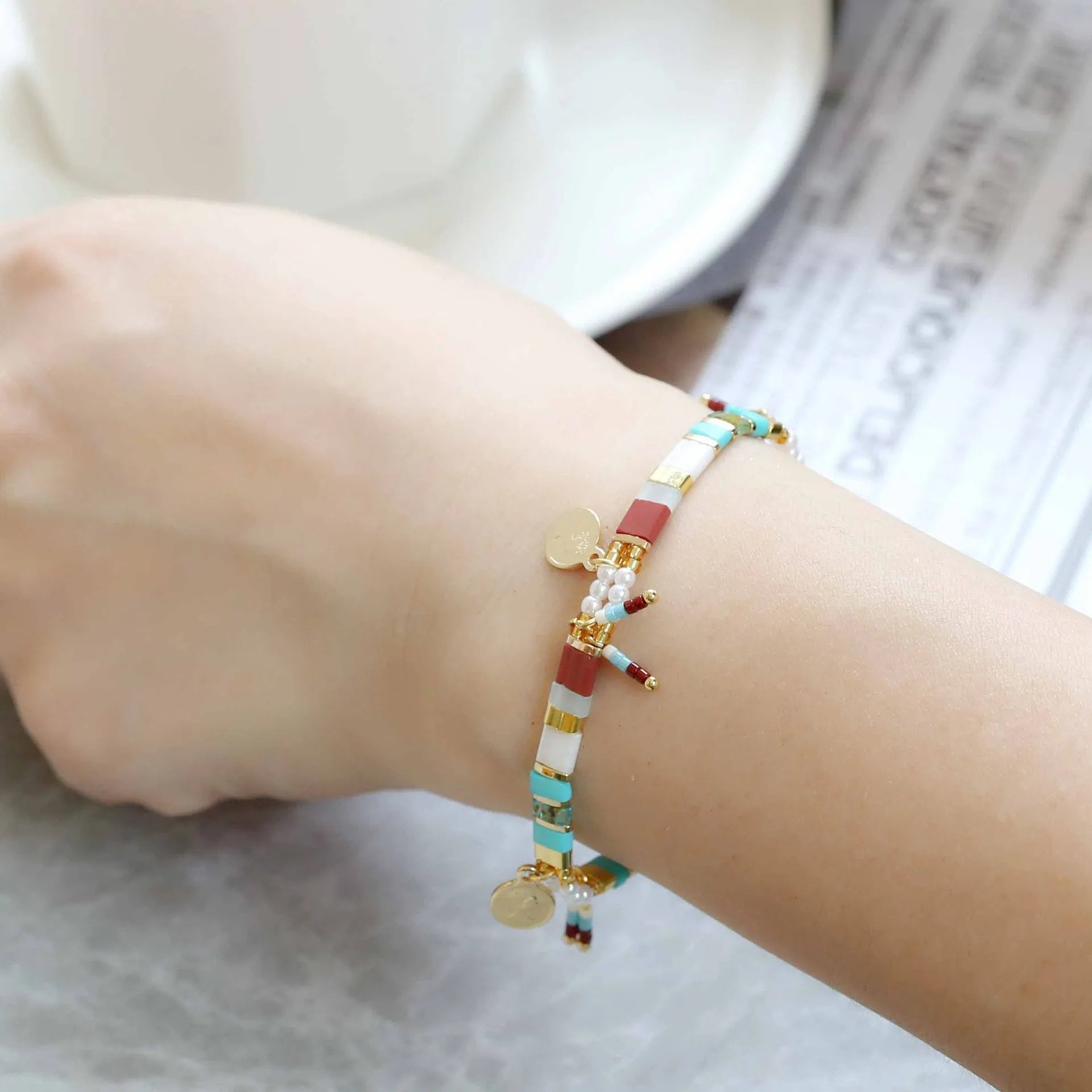 Handcrafted women's bracelet featuring imitation pearls and coloured glass beads on a wrist.