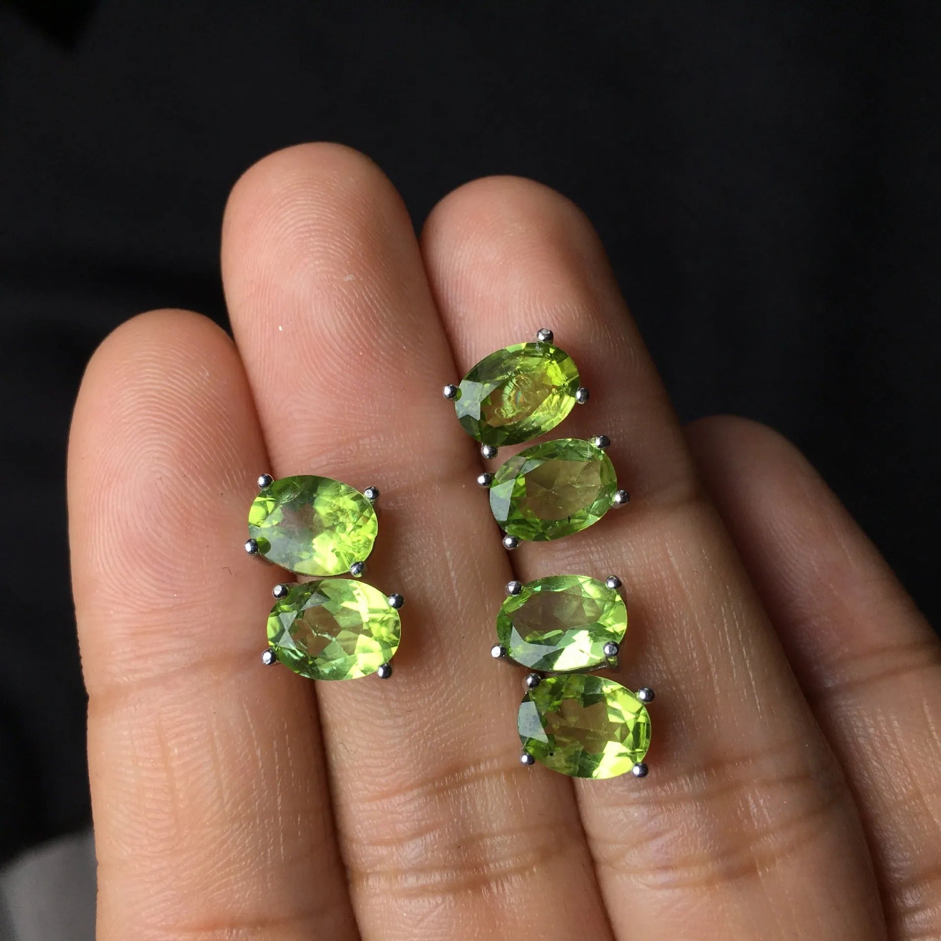 Natural grass green olivine faceted stud earrings in S925 silver settings on a white background.