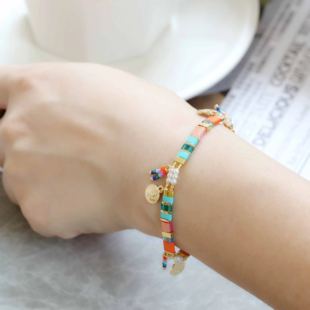 Handcrafted women's bracelet featuring imitation pearls and coloured glass beads on a wrist.