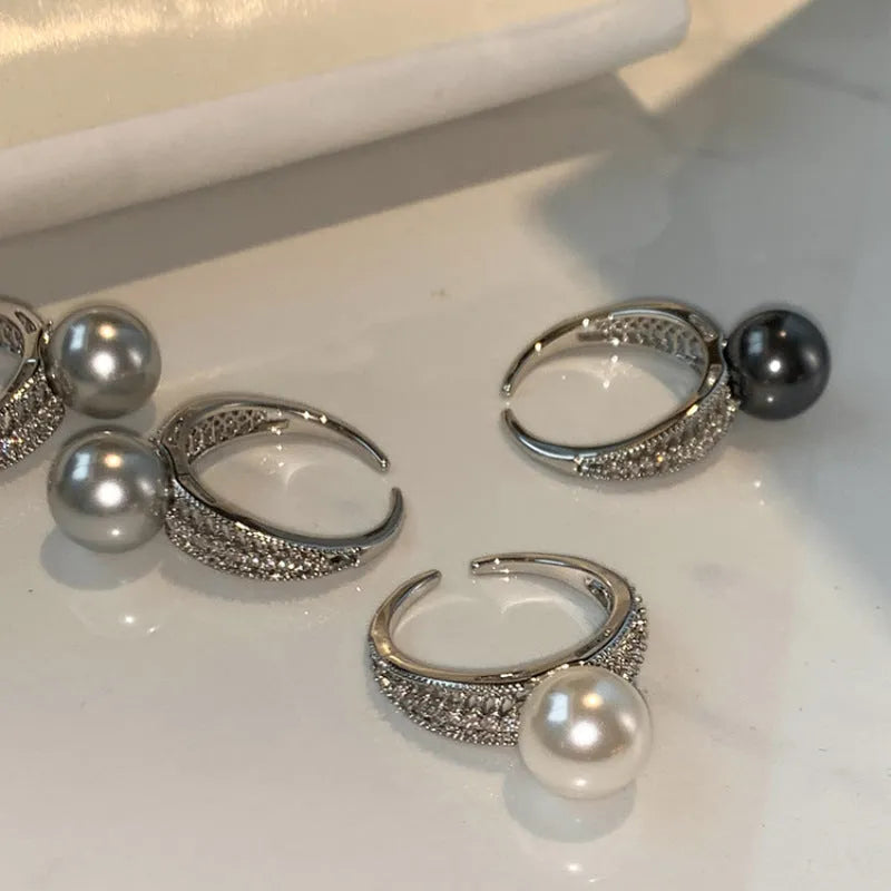 Adjustable black geometric pearl copper ring for women on a finger.