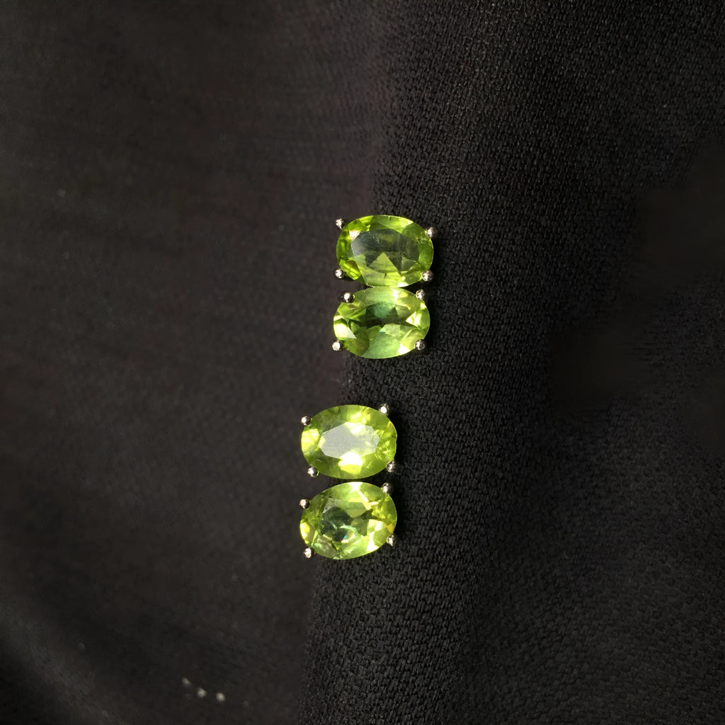 Natural grass green olivine faceted stud earrings in S925 silver settings on a white background.
