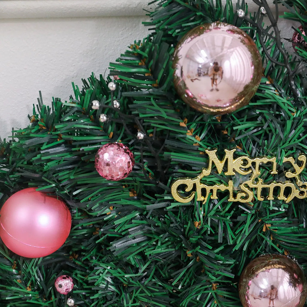 Pink artificial Christmas rattan garland with small berries and warm white LED lights draped on a mantelpiece.