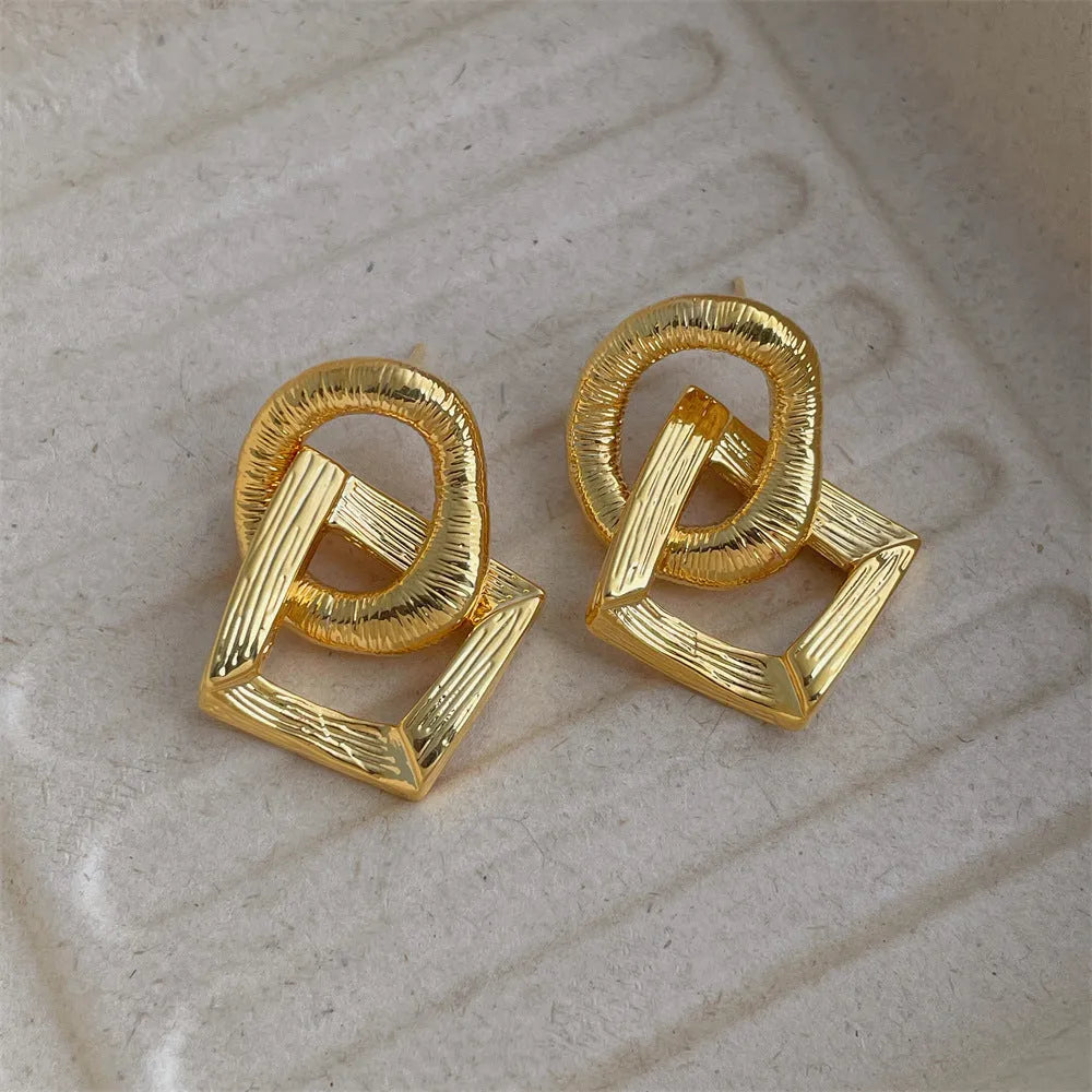 Geometric circle drop pendant earrings in gold or silver finish, showing 3.4cm length on a copper base.