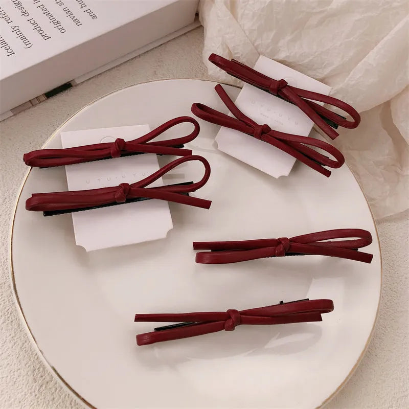 Wine red leather bow hair clip barrette on a white background.