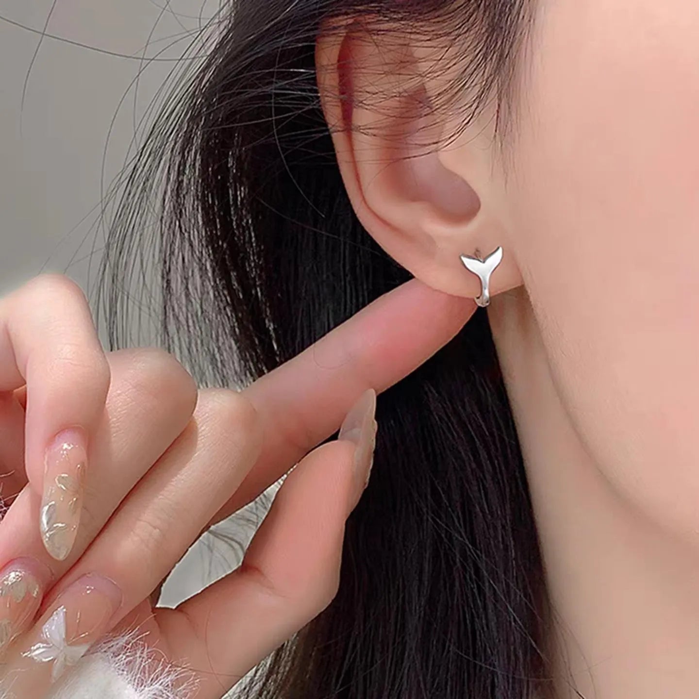 Women's fishtail design earrings in electroplated White Gold colour on a white background.