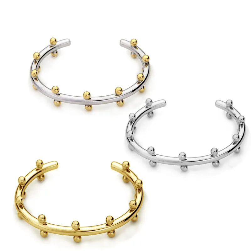 Stainless steel C-shaped bracelet with textured bean beads in gold finish.