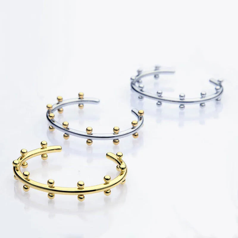 Stainless steel C-shaped bracelet with textured bean beads in gold finish.