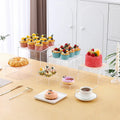 White and transparent plastic dessert display cube sets showing stackable 6-piece arrangements for cakes and pastries