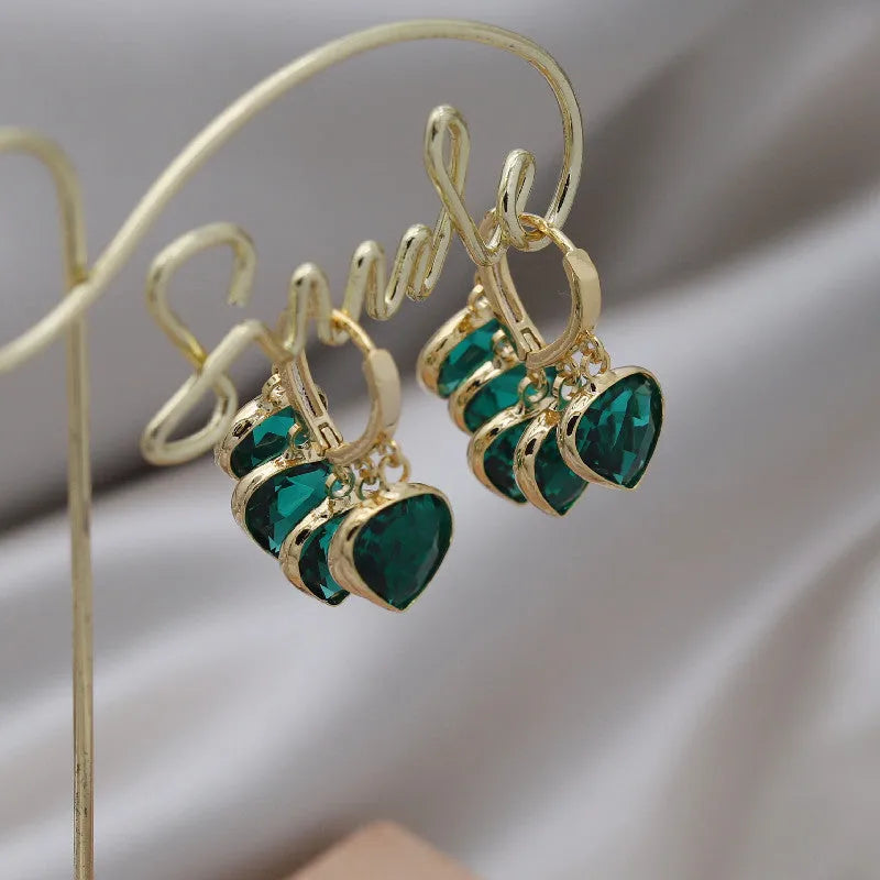 Pair of green heart-shaped glass pendant ear clip earrings with alloy and artificial gemstone details.
