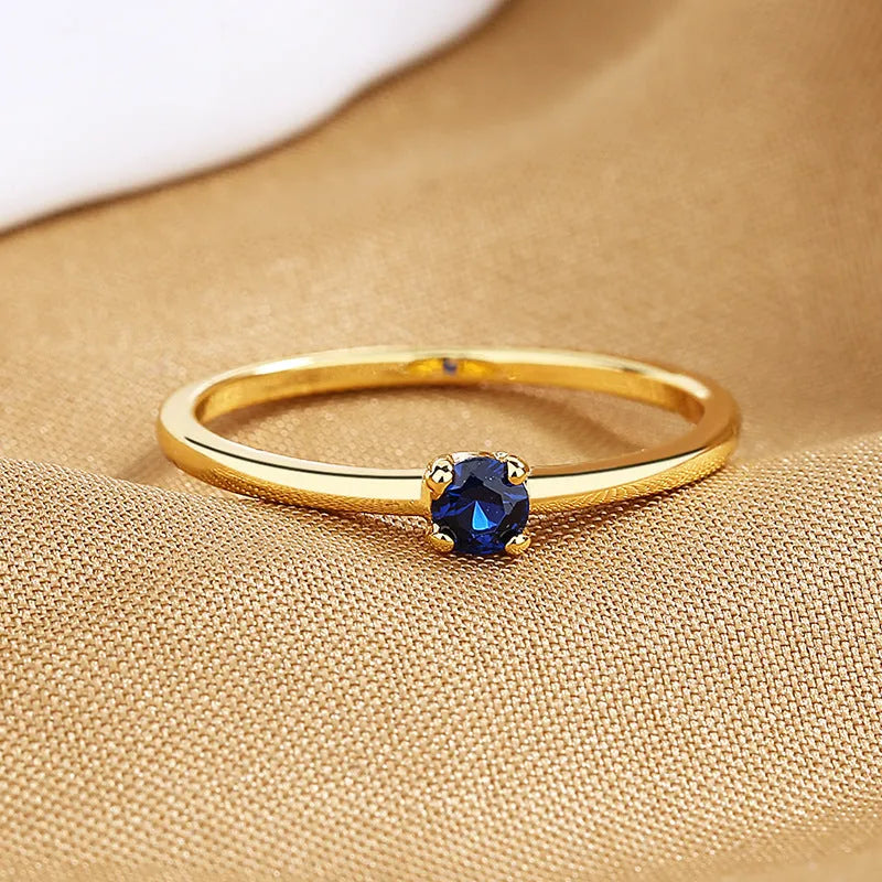 Copper geometric ring with a single diamond shape on a round band, shown in white, red, green, and blue colour options.