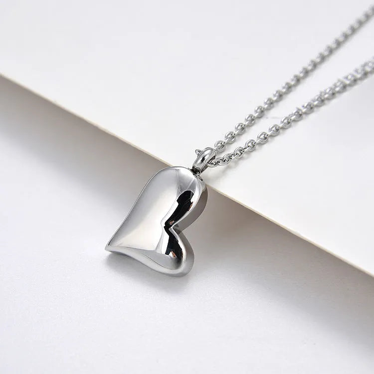 Silver stainless steel necklace with a curved peach heart pendant on an adjustable chain.