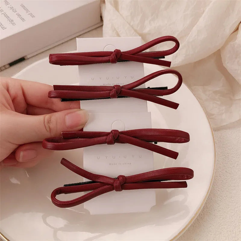 Wine red leather bow hair clip barrette on a white background.