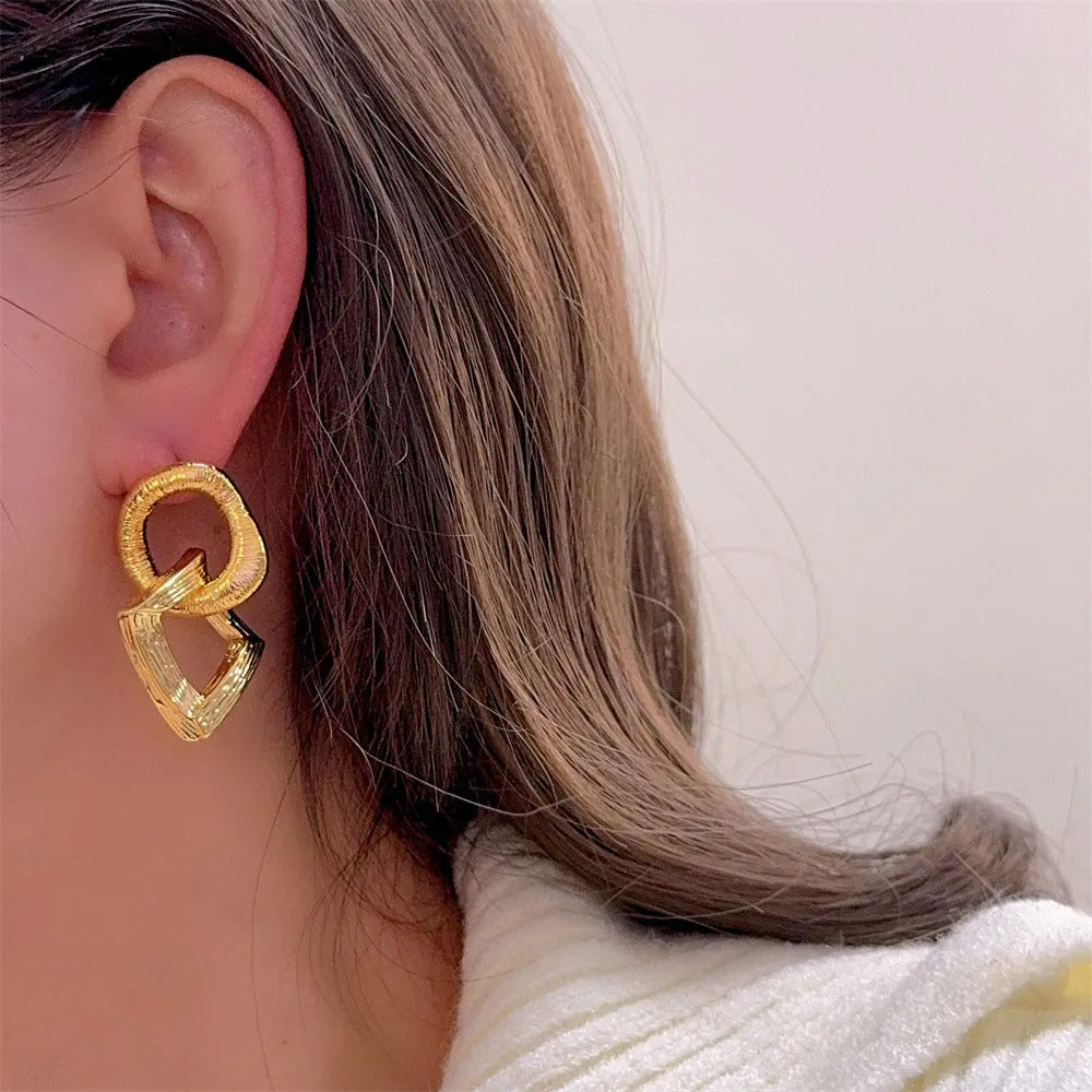 Geometric circle drop pendant earrings in gold or silver finish, showing 3.4cm length on a copper base.