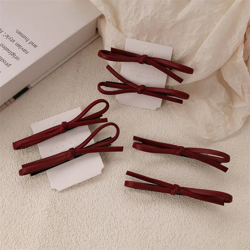 Wine red leather bow hair clip barrette on a white background.