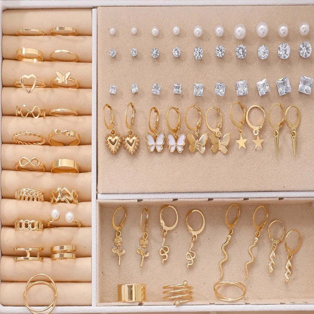 108 gold and yellow alloy stud earrings with geometric shapes and round pearl details on a plain surface.