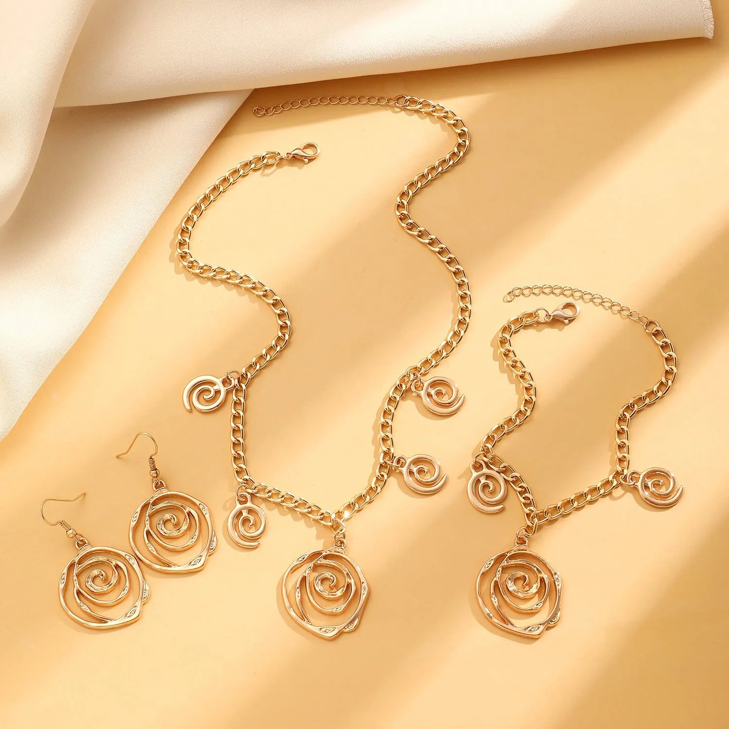 Spiral donut jewellery set showing necklace, bracelet and ear hooks in gold finish with geometric circle design