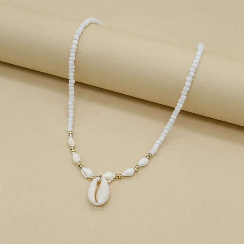 White conch shell necklace with mother of pearl pendant and beads on a chain.
