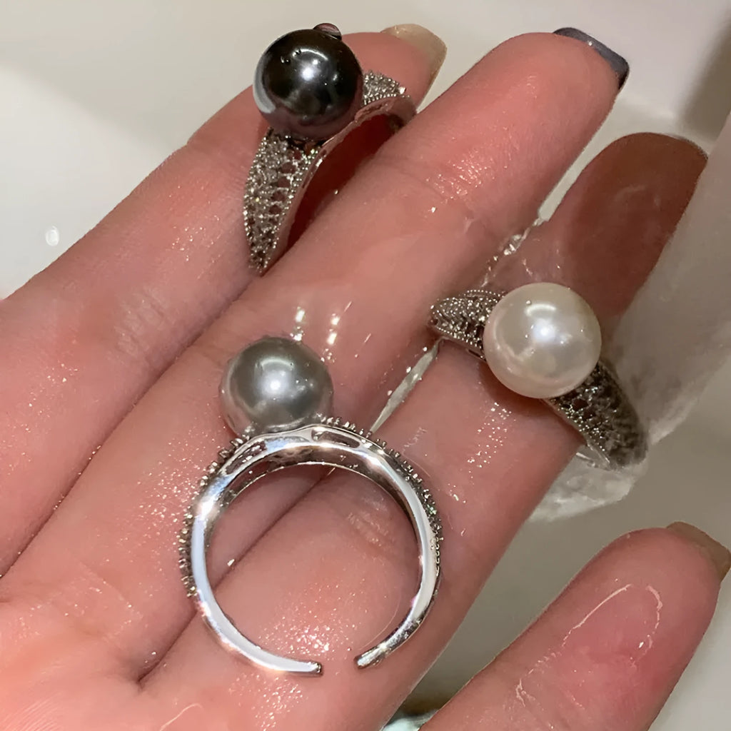Adjustable black geometric pearl copper ring for women on a finger.