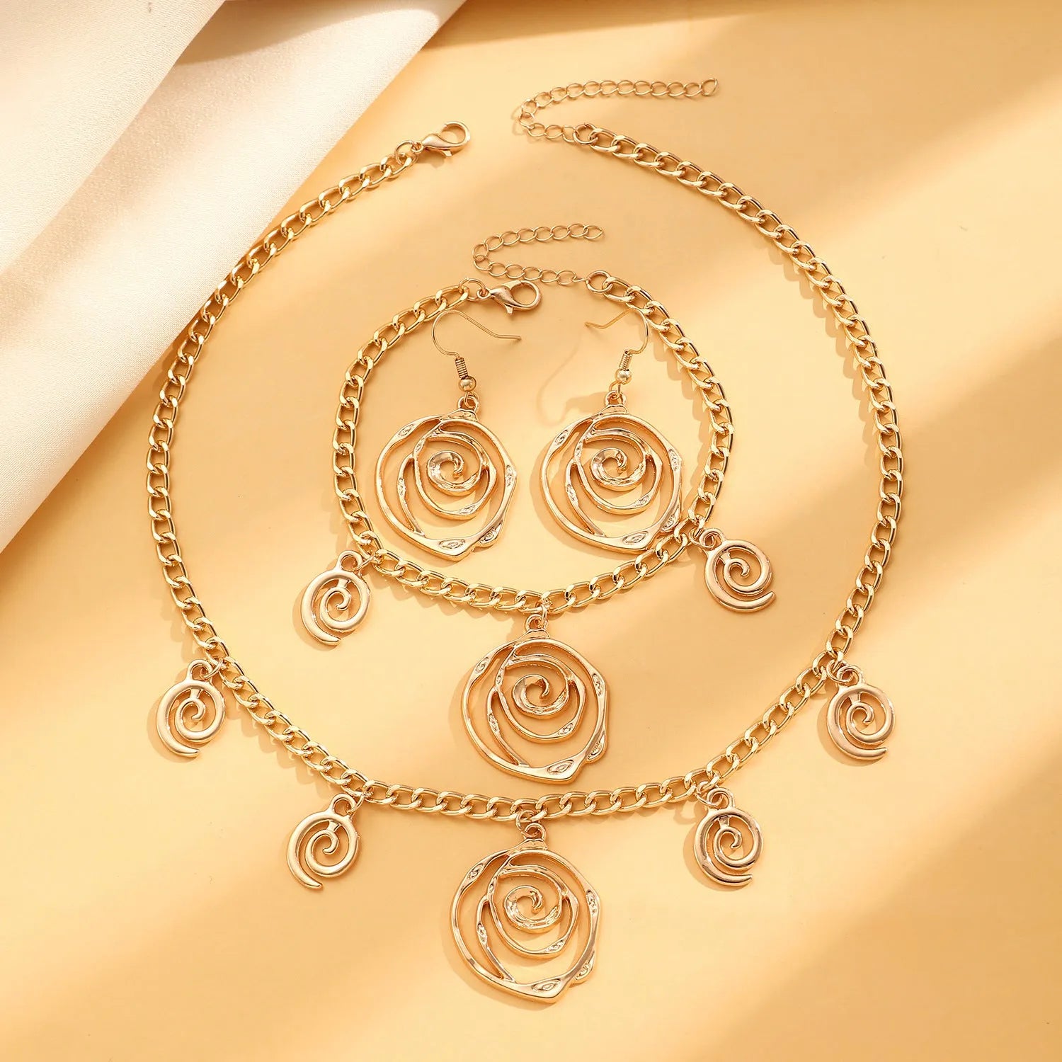 Spiral donut jewellery set showing necklace, bracelet and ear hooks in gold finish with geometric circle design