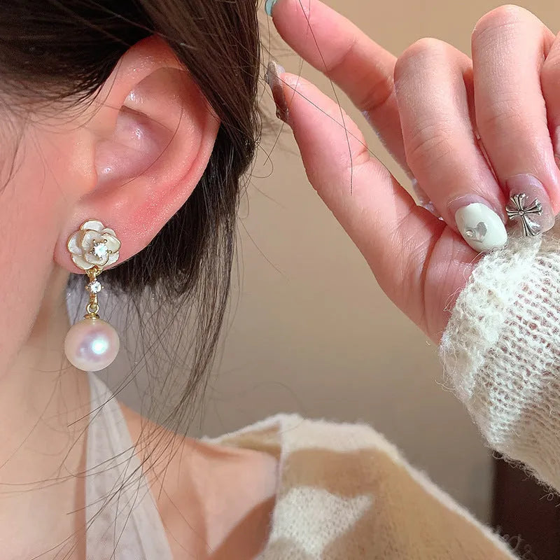 A pair of alloy camellia flower stud earrings for women with a faux pearl centre.