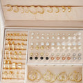 108 gold and yellow alloy stud earrings with geometric shapes and round pearl details on a plain surface.