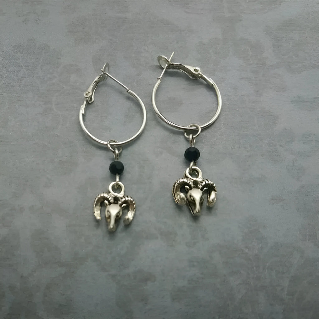Silver Tibetan antelope round ring drop dangle earrings on a white background.
