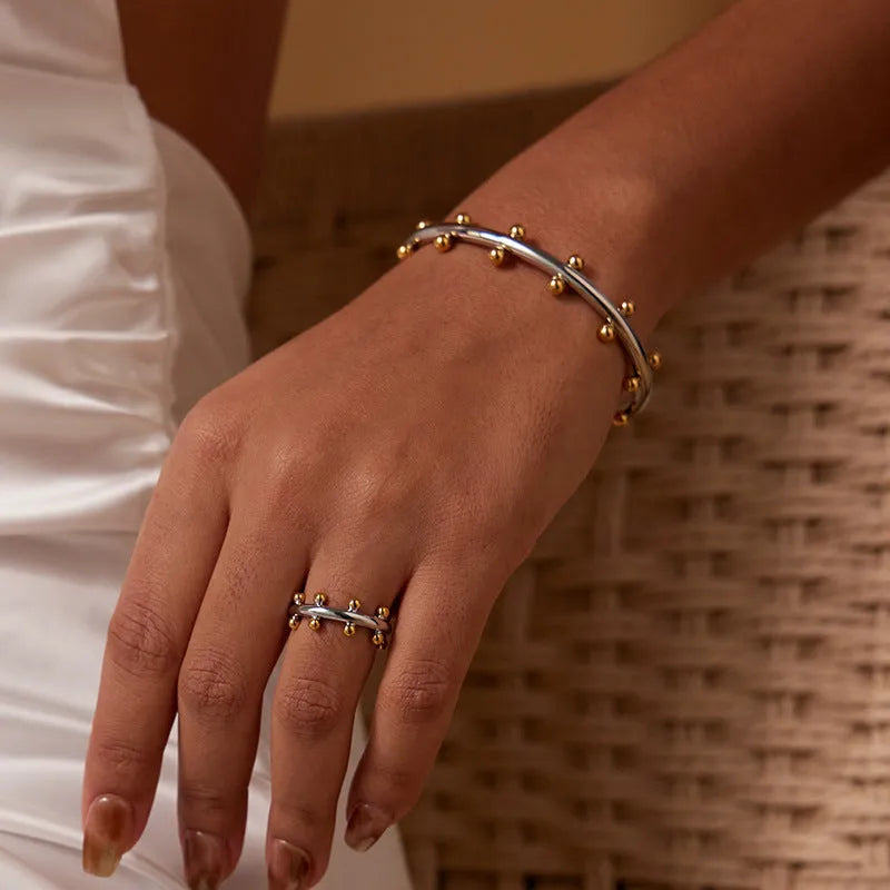 Stainless steel C-shaped bracelet with textured bean beads in gold finish.