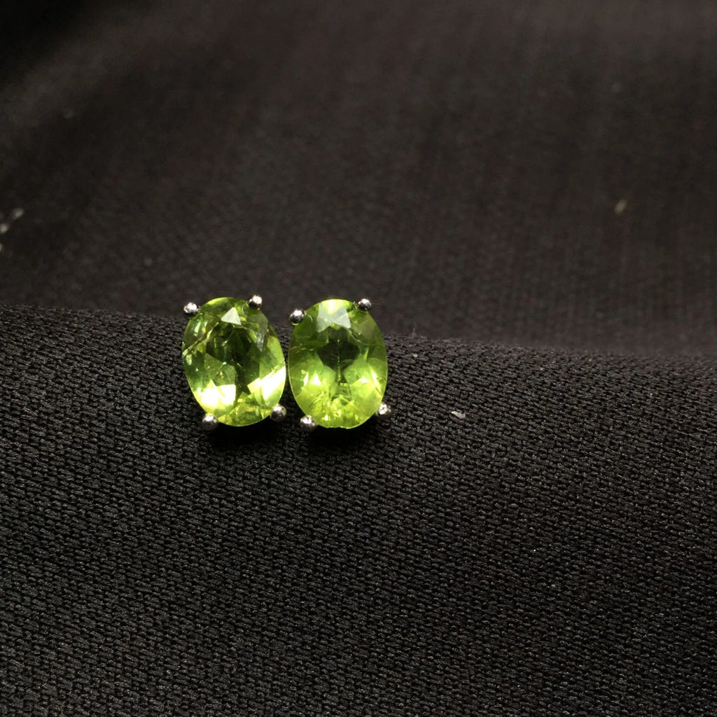Natural grass green olivine faceted stud earrings in S925 silver settings on a white background.