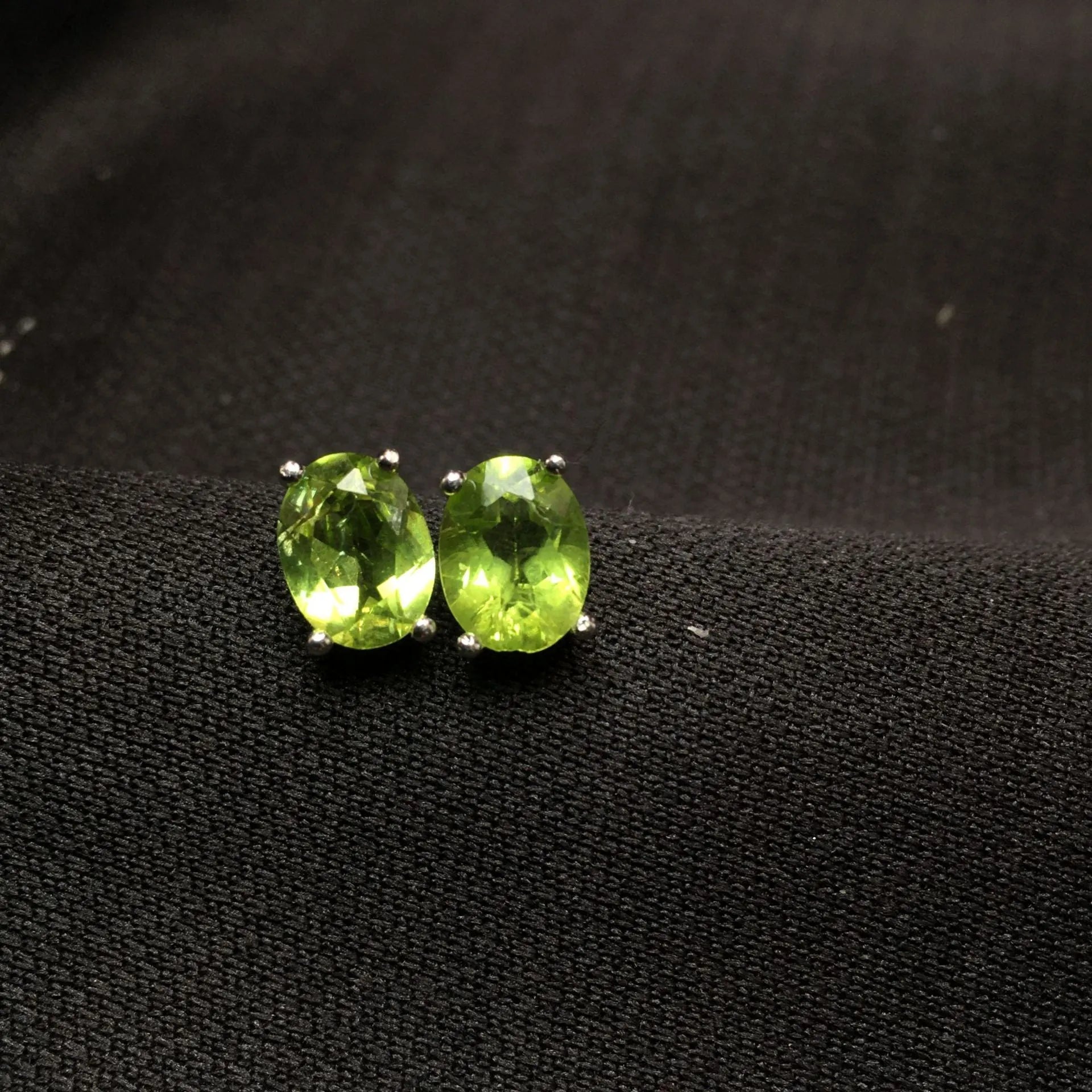 Natural grass green olivine faceted stud earrings in S925 silver settings on a white background.